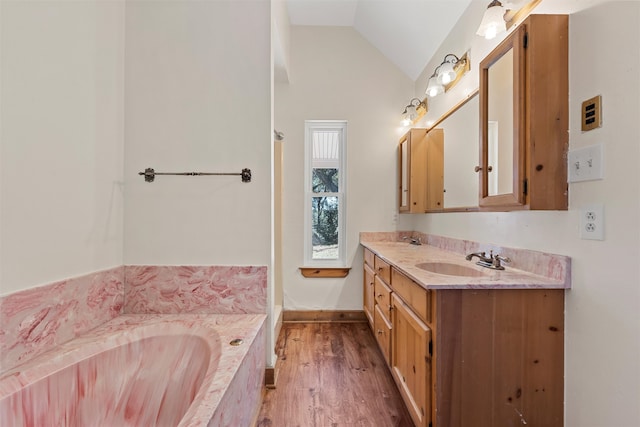 bathroom featuring lofted ceiling, tiled bath, vanity, and hardwood / wood-style floors