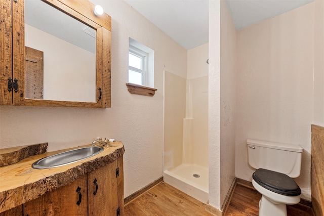 bathroom featuring walk in shower, wood-type flooring, vanity, and toilet