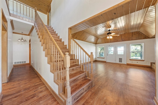 stairs featuring hardwood / wood-style flooring, ceiling fan with notable chandelier, vaulted ceiling, and wooden ceiling