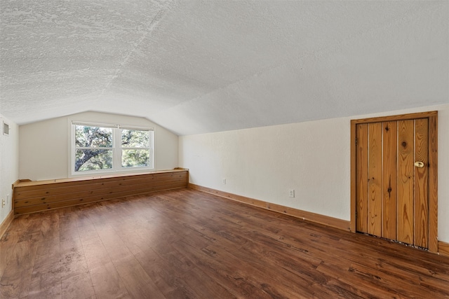 bonus room with a textured ceiling, lofted ceiling, and dark hardwood / wood-style flooring