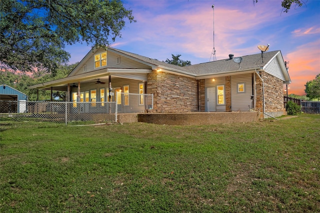 back house at dusk featuring a lawn