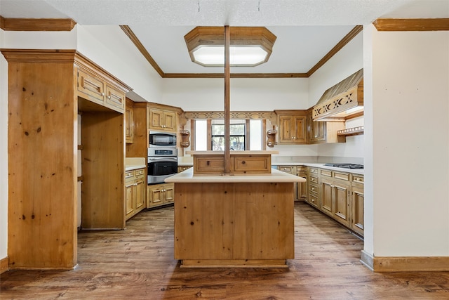 kitchen with crown molding, a kitchen island, hardwood / wood-style floors, and stainless steel appliances