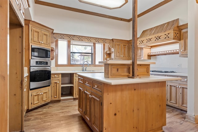 kitchen featuring a center island, sink, light hardwood / wood-style flooring, stainless steel appliances, and ornamental molding