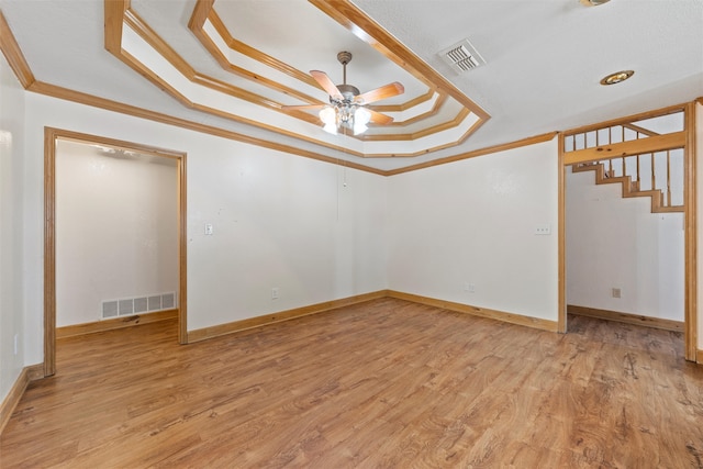 spare room with ceiling fan, light hardwood / wood-style flooring, crown molding, and a tray ceiling