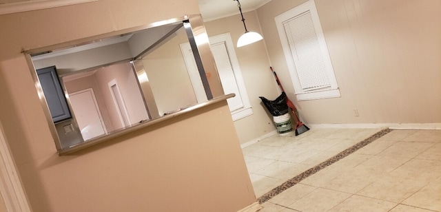 hallway with crown molding and light tile patterned floors