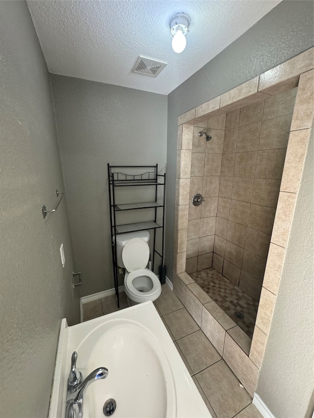 bathroom featuring sink, a textured ceiling, toilet, and tiled shower