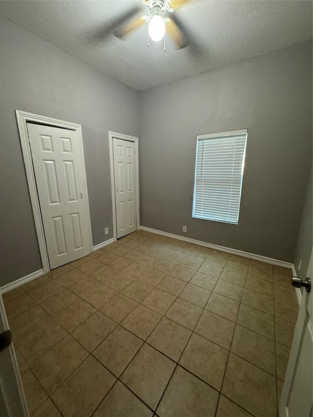 spare room with a textured ceiling, light tile patterned flooring, and ceiling fan