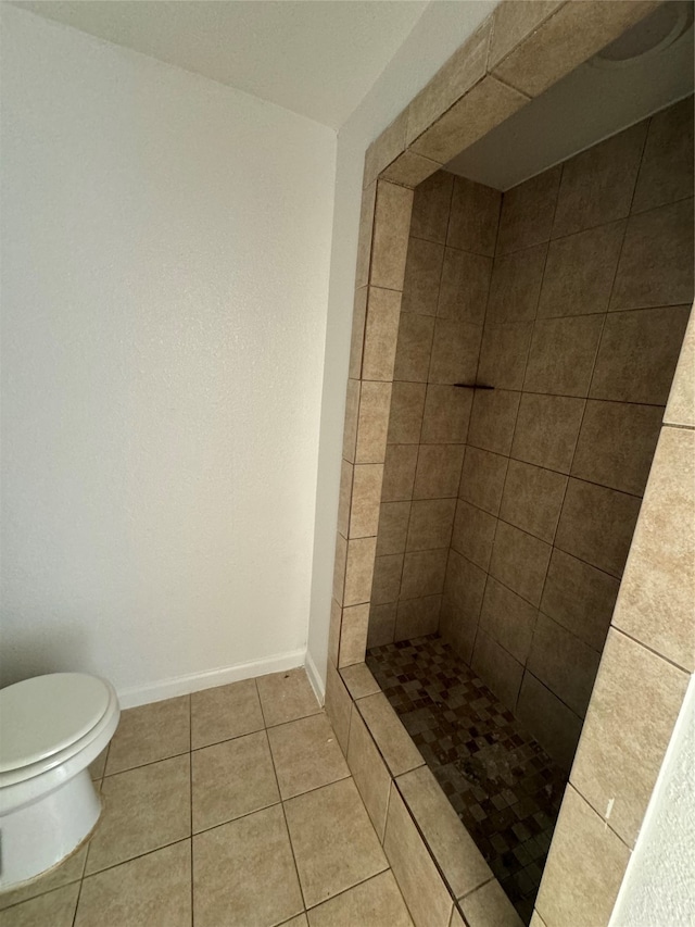 bathroom featuring tiled shower, toilet, and tile patterned floors