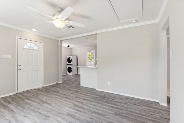 entrance foyer with stacked washer and clothes dryer, hardwood / wood-style flooring, ceiling fan, and crown molding