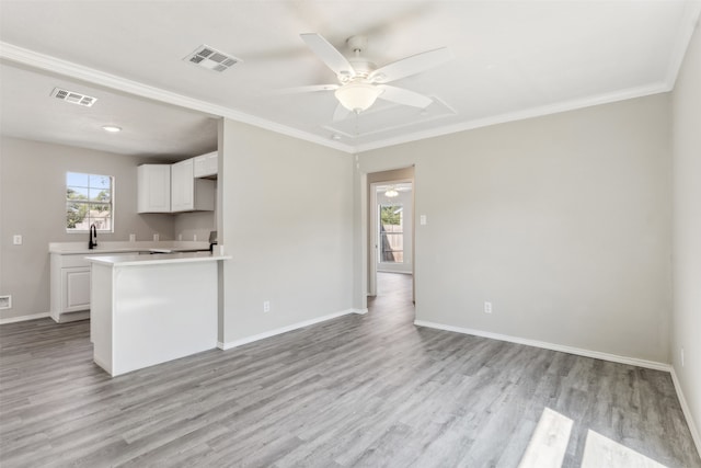 kitchen featuring kitchen peninsula, ornamental molding, ceiling fan, white cabinetry, and light wood-type flooring