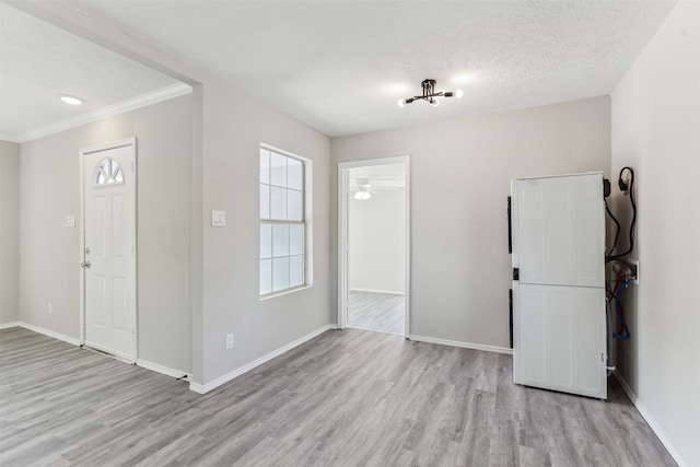 entryway with ornamental molding, light wood-type flooring, a textured ceiling, and ceiling fan