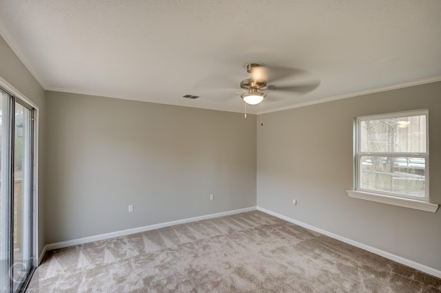 carpeted spare room featuring a healthy amount of sunlight, crown molding, and ceiling fan