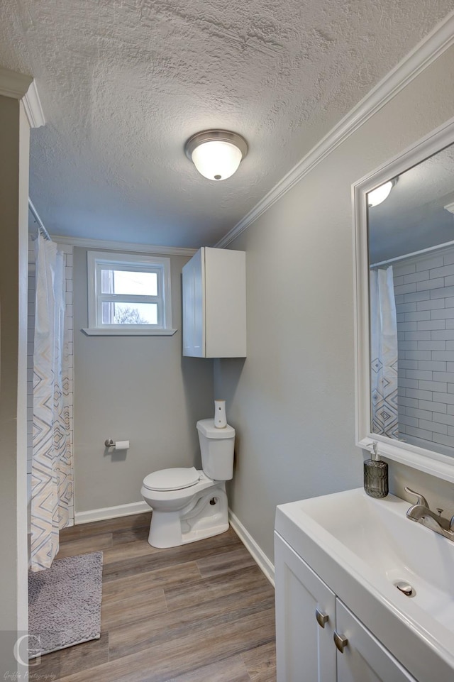 bathroom featuring hardwood / wood-style floors, a textured ceiling, vanity, toilet, and ornamental molding