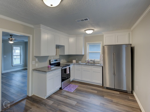 kitchen featuring white cabinetry, hardwood / wood-style floors, appliances with stainless steel finishes, ornamental molding, and light stone counters