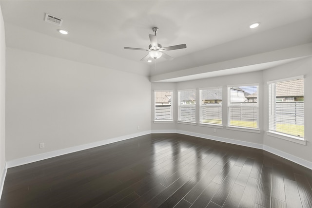 spare room with a healthy amount of sunlight, ceiling fan, and dark hardwood / wood-style flooring