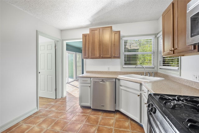 kitchen featuring a textured ceiling, sink, light tile patterned floors, and stainless steel appliances