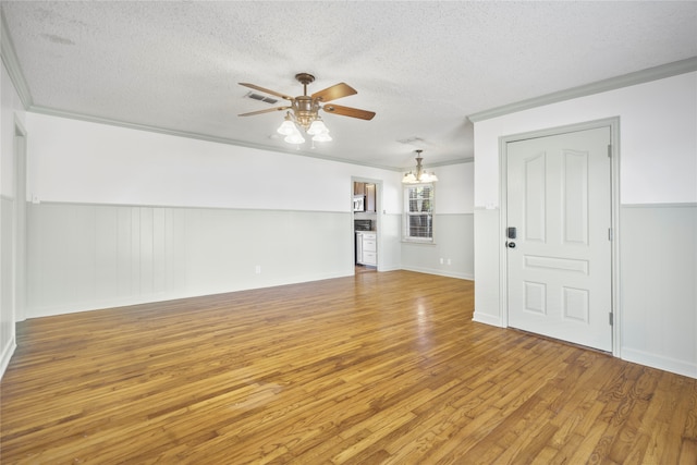 unfurnished living room featuring a textured ceiling, wood-type flooring, ceiling fan with notable chandelier, and ornamental molding