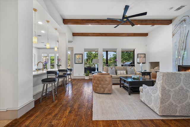 living room featuring beamed ceiling, ceiling fan, and dark wood-type flooring