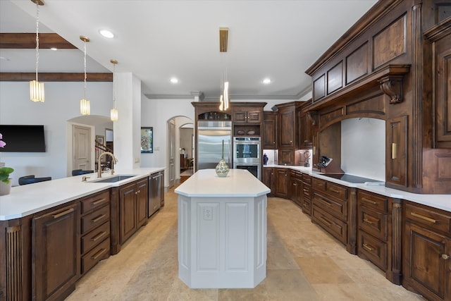 kitchen featuring appliances with stainless steel finishes, a large island with sink, pendant lighting, dark brown cabinets, and sink