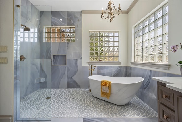 bathroom with tile walls, independent shower and bath, an inviting chandelier, ornamental molding, and vanity