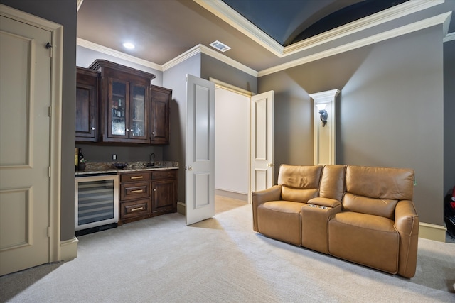 home theater room featuring wine cooler, light colored carpet, wet bar, and crown molding