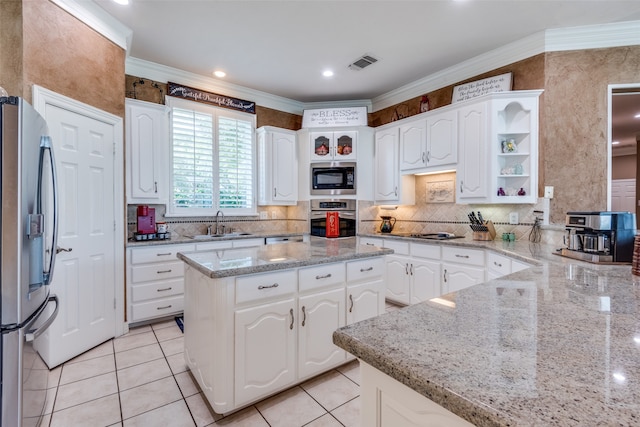 kitchen with light stone counters, light tile patterned flooring, white cabinetry, stainless steel appliances, and crown molding