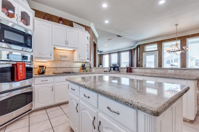 kitchen featuring an inviting chandelier, appliances with stainless steel finishes, a center island, and ornamental molding