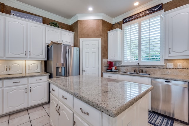 kitchen with appliances with stainless steel finishes, ornamental molding, sink, and white cabinetry