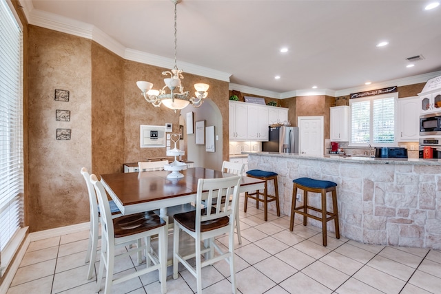 dining space with light tile patterned flooring, crown molding, and a chandelier