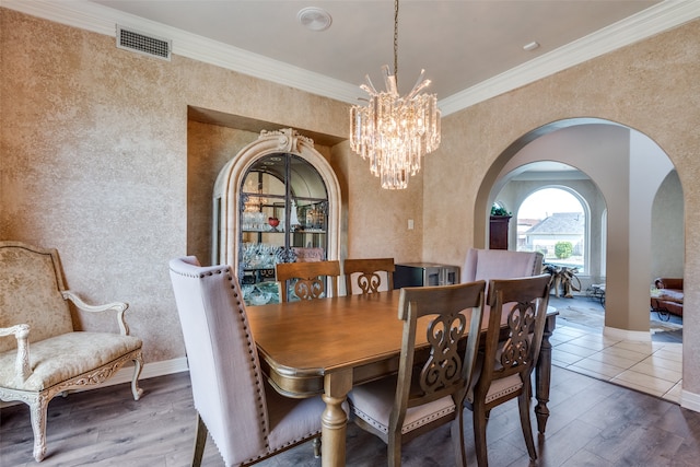 dining area featuring a notable chandelier, ornamental molding, and hardwood / wood-style flooring