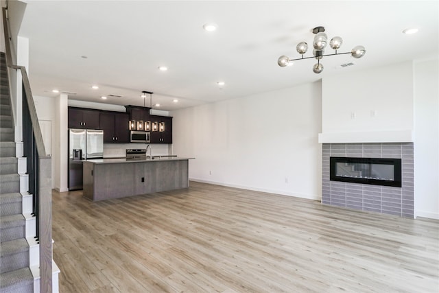 unfurnished living room with light hardwood / wood-style flooring, a tiled fireplace, and sink