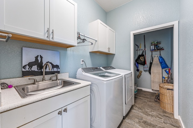 clothes washing area featuring washing machine and dryer, cabinets, sink, and hardwood / wood-style flooring