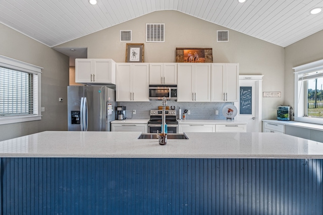 kitchen with wood ceiling, lofted ceiling, white cabinetry, stainless steel appliances, and light stone countertops