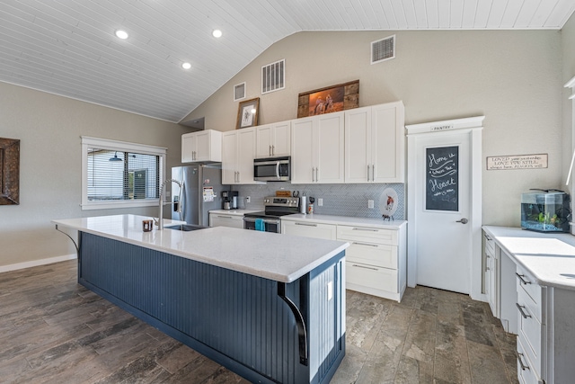 kitchen featuring stainless steel appliances, an island with sink, wood ceiling, and a kitchen breakfast bar