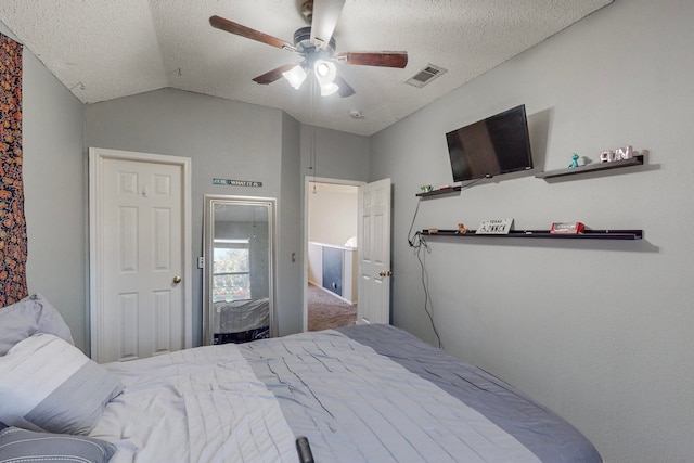 bedroom with ceiling fan, vaulted ceiling, and a textured ceiling