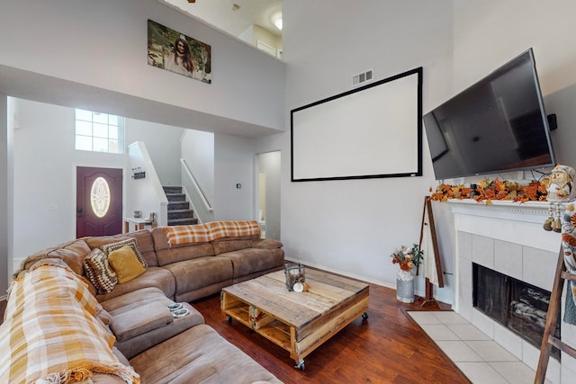 living room featuring a tiled fireplace, light hardwood / wood-style floors, and a high ceiling