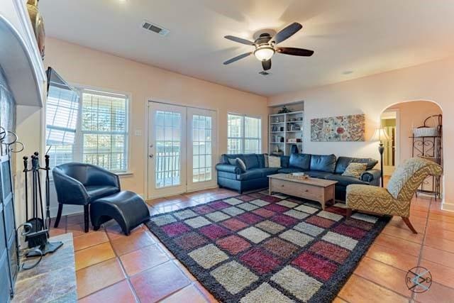 tiled living room featuring ceiling fan and built in shelves