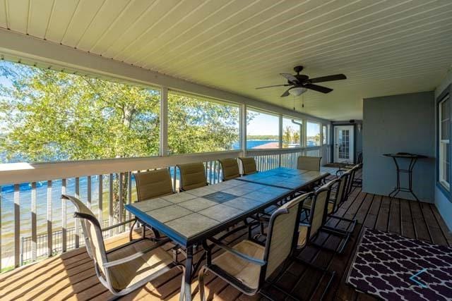 wooden terrace with a water view and ceiling fan