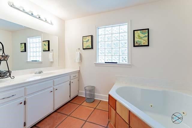 bathroom featuring tile patterned flooring, vanity, and a tub to relax in