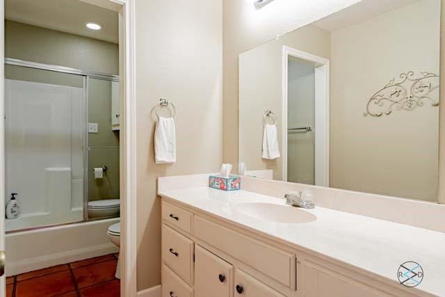 full bathroom featuring bath / shower combo with glass door, tile patterned floors, vanity, and toilet