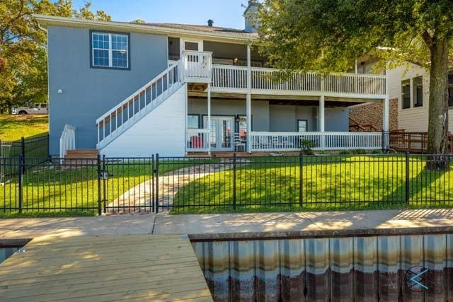 rear view of property featuring a balcony and a yard