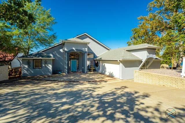 view of front of property featuring concrete driveway, an attached garage, and stucco siding