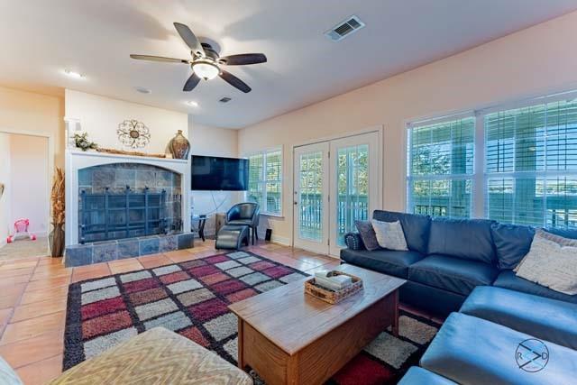 tiled living room with a tiled fireplace and ceiling fan