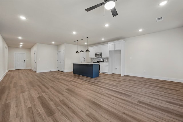 unfurnished living room with sink, light hardwood / wood-style flooring, and ceiling fan