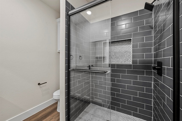 bathroom featuring wood-type flooring, a shower with door, and toilet