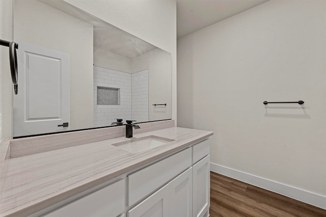 bathroom featuring a tile shower, hardwood / wood-style flooring, and vanity