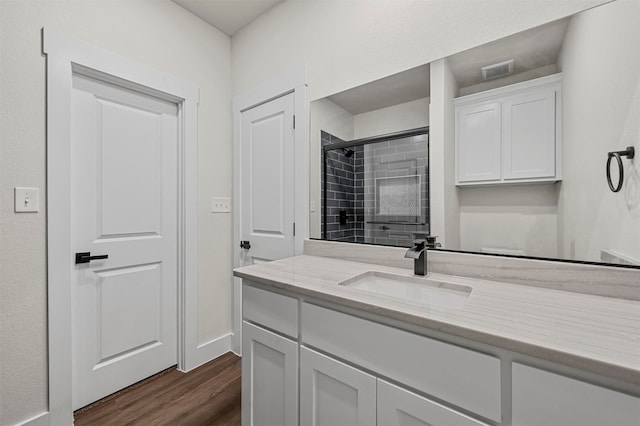 bathroom with tiled shower, vanity, and hardwood / wood-style flooring