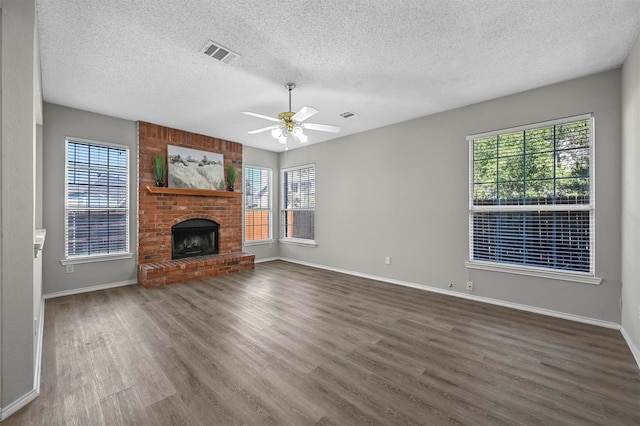 unfurnished living room featuring a textured ceiling, a fireplace, ceiling fan, and dark wood-type flooring