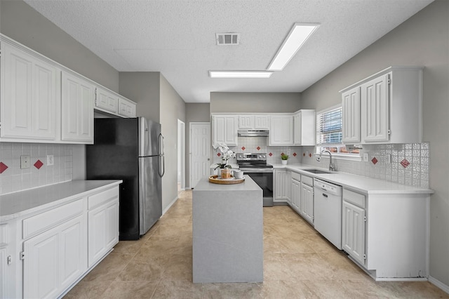 kitchen featuring sink, backsplash, white cabinetry, stainless steel appliances, and a center island