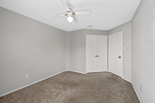 unfurnished bedroom with a textured ceiling, ceiling fan, and dark carpet